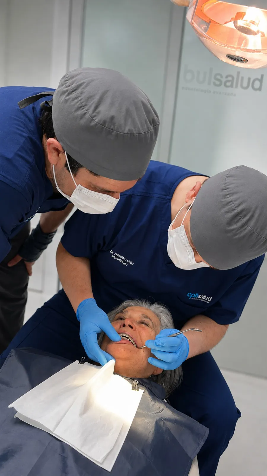 Dr. Francisco Ortiz y su ayudante instalando un implante dental a una paciente en el pabellón de CPH Salud