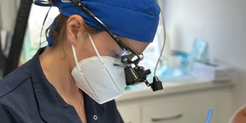 Odontóloga de CPH Salud con lupas de aumento concentrada en un tratamiento conservador